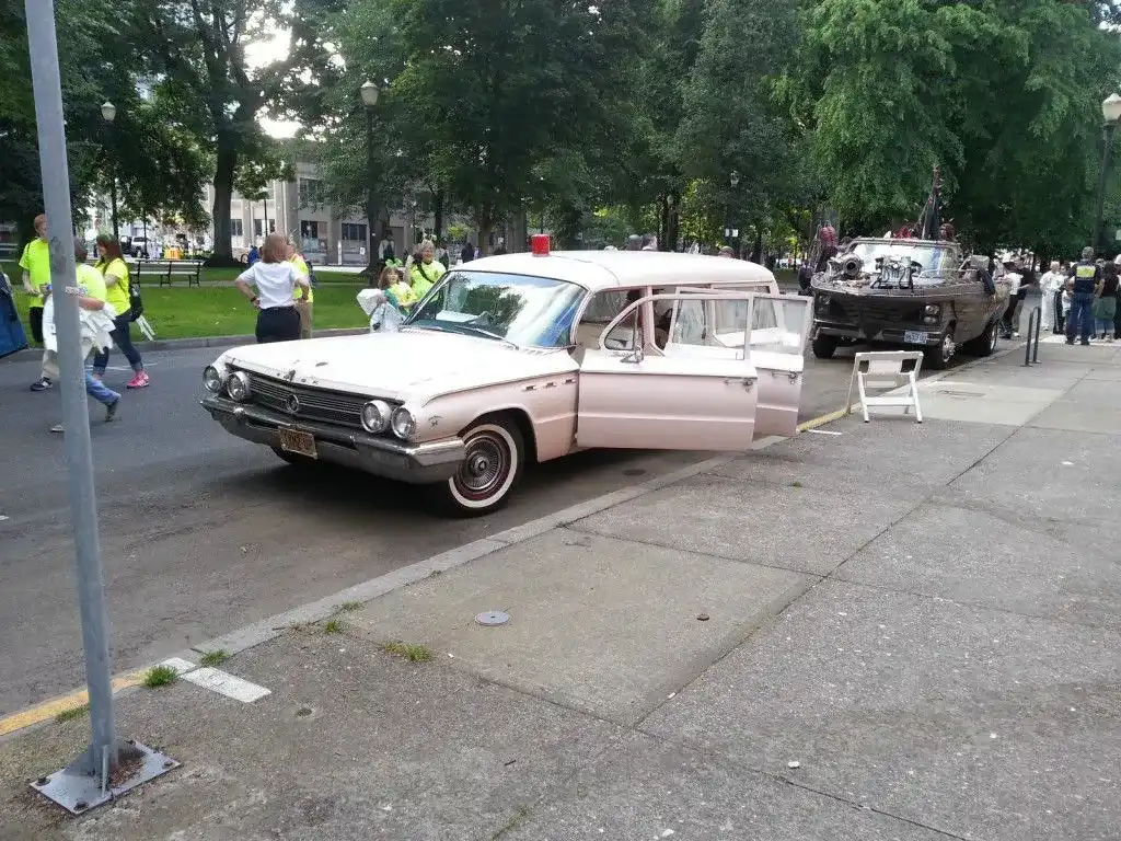 1962 Buick Premier Flxible Hearse doors open, onlooking crowd.
