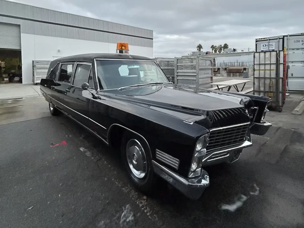 Black 1967 vintage Cadillac hearse with an orange rooftop light.